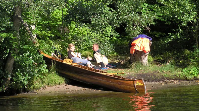 Foto af folk, der har sat kano i and langs bredden